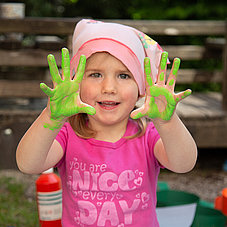Child with finger paint on her hands at the Minihaus München crèche