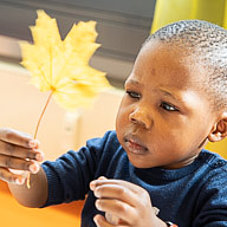 Kind bastelt mit herbstlichen Blättern in der Kinderkrippe Sendling
